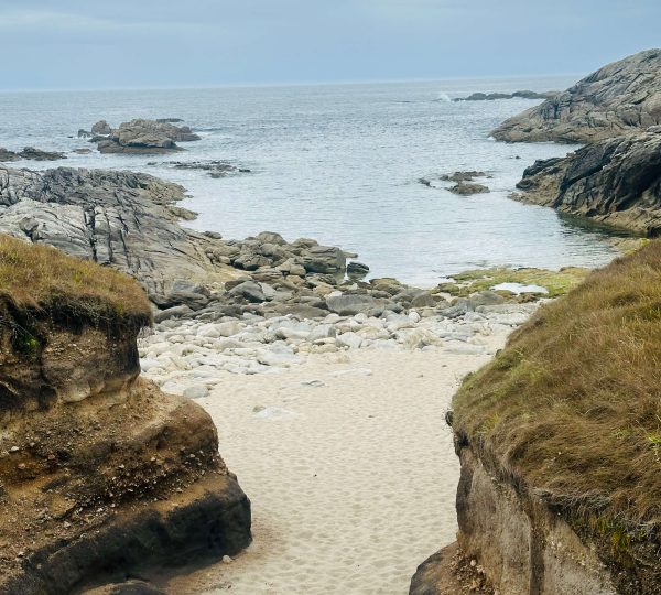 Pequeña cala de arena entre rocas en la costa de Laxe