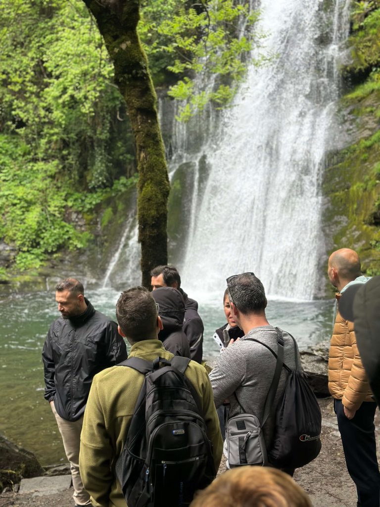 Participantes de una escapada para solteros visitando una cascada durante una ruta por el Geoparque Montañas do Courel.