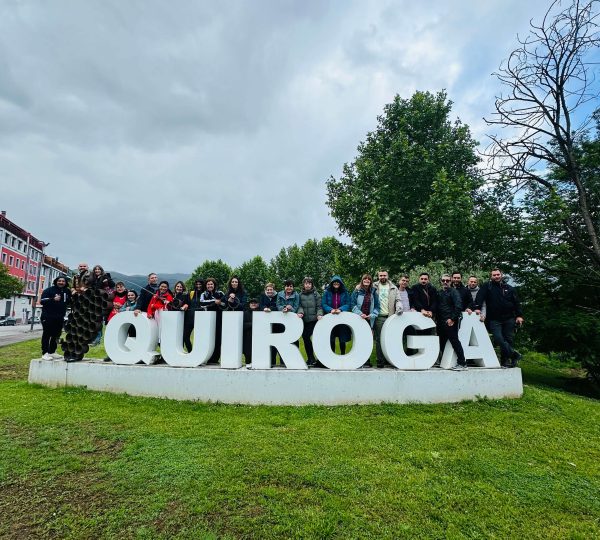 Grupo de participantes de un evento para solteros posando junto al cartel de Quiroga en Galicia.